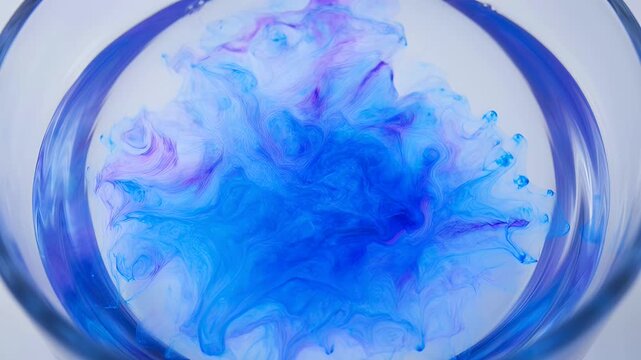 Swirling blue and pink ink forms abstract clouds within a transparent circular vessel