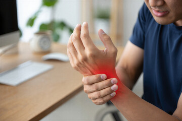Man holding wrist with red pain indicator at desk wrist pain