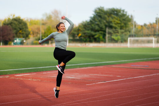 Female athlete doing dynamic knee lift exercise on running track