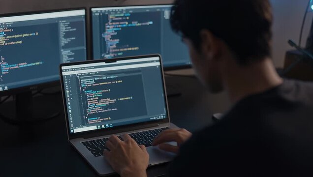 Young Male Asian Programmer Coding on Laptop in Modern Workspace