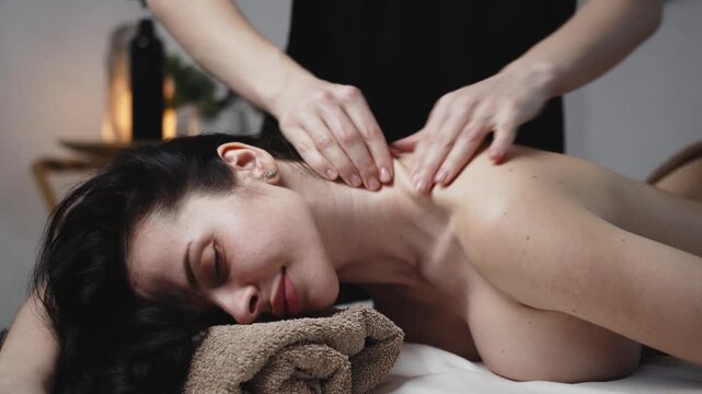 Professional therapist giving back massage to woman in calm spa setting. Spa treatment, relaxation and wellness concept.
