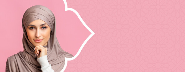 Naklejka premium A young woman is shown in a headscarf. She has a gentle look on her face and rests her chin on her hand. The background is pastel pink with a subtle design.