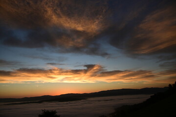 Fototapeta premium stunning sunrise between the fog and clouds in the coastal mountains