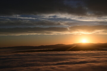 Fototapeta premium cloudy sunrise above the fog and below the clouds