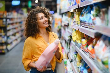 Woman shopping for laundry detergent in supermarket aisle