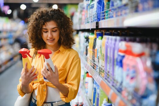 Woman comparing cleaning products in supermarket aisle