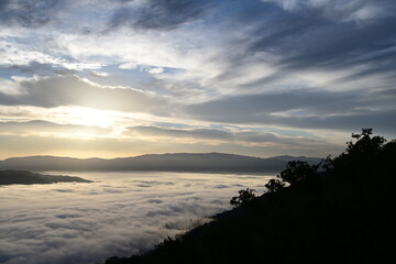 Obraz premium cloudy sunrise above the fog and below the clouds