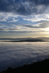 Fototapeta premium cloudy sunrise above the fog and below the clouds