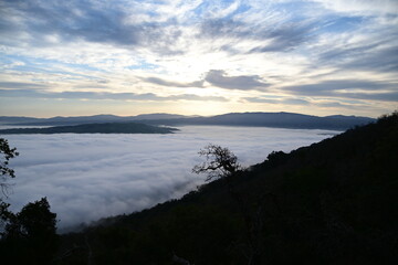 Fototapeta premium cloudy sunrise above the fog and below the clouds