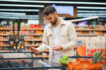 Man choosing frozen food in supermarket with cart © Serhii
