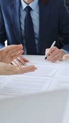 Obraz premium Businessman signing a contract papers at the white desk in office, colleagues applauding to the successful results of negotiations. Business people concept
