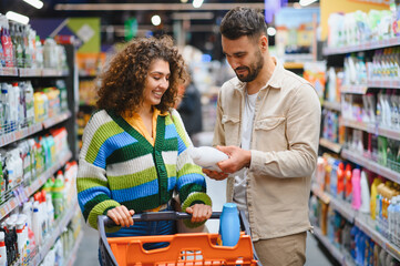 Couple shopping for household products in supermarket aisle