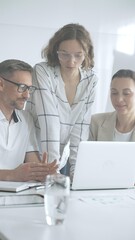 Fototapeta premium Business people team collaborating on a project, analyzing data on a laptop during a productive office meeting, fostering teamwork and strategic planning