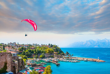 Naklejka premium Happy people parasailing on Old town of Antalya Beach in summer - Aerial view of Antalya old town or harbour (Kaleici), Bay with ships and boats in summer - Antalya, Turkey 