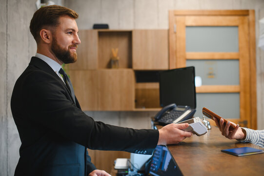 Businessman processing contactless payment at hotel reception desk