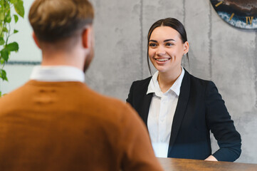 Friendly female receptionist assisting client at hotel counter