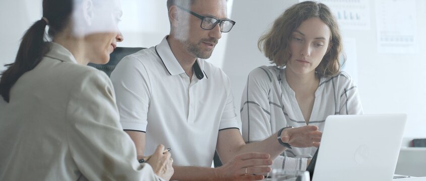 Business team collaborating and analyzing data on a laptop during a productive office meeting, discussing strategies and making informed decisions