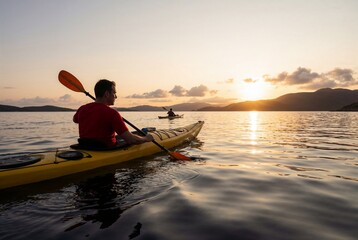 Fototapeta premium Man kayaking alone on serene lake at sunset with paddle in hand.