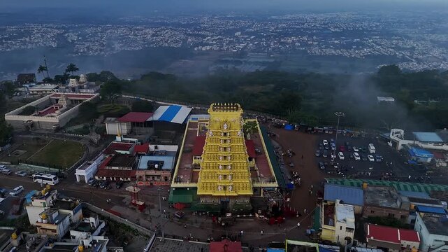 Cinematic drone view of golden Sri Chamundeshwari Temple atop Chamundi Hills on misty day