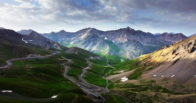 Aerial drone view of the winding mountain road on the Duku Highway, passing through green valleys in the Tianshan Mountains, Xinjiang, China