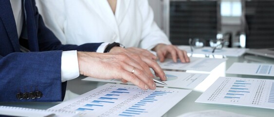 Business people hands discussing financial data and analyzing growth charts on a laptop screen during a corporate meeting with paper documents, showing teamwork and strategy planning