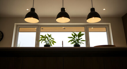 Obraz premium Three pendant lights illuminating two potted plants on a countertop in front of a window