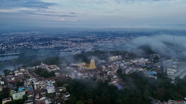 Cinematic drone view of Sri Chamundeshwari Temple atop Chamundi Hills amid misty cityscape in mysore