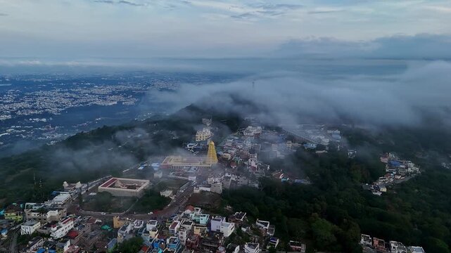 Cinematic drone view of Sri Chamundeshwari Temple atop Chamundi Hills amid misty cityscape in mysore