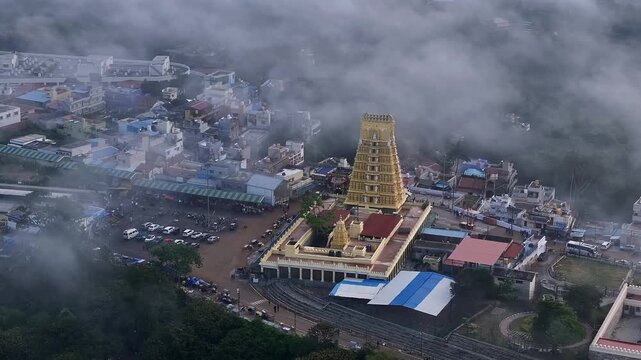 Cinematic drone view of Sri Chamundeshwari Temple atop Chamundi Hills amid misty cityscape in mysore