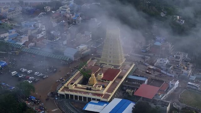 Cinematic drone view of Sri Chamundeshwari Temple atop Chamundi Hills amid misty cityscape in mysore