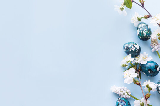 Easter flat lay. Stylish easter eggs and cherry flowers on blue background. Easter celebration, season greetings mockup. Spring modern floral banner