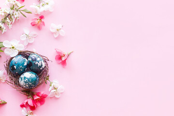 Easter flat lay. Stylish easter eggs in nest and cherry flowers on pink background. Easter celebration, season greetings mockup. Spring modern floral banner © sonyachny