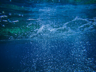 Naklejka premium Underwater background with water bubbles and undersea light rays shine. Dark blue ocean surface seen from underwater. Sunbeams and Sea deep or ocean underwater a Abstract background. sunlight Nature.