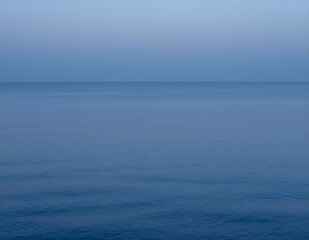 Obraz premium Serene Calm Ocean Horizon at Dusk with Smooth Water Surface and Soft Gradient Sky Perfect for Meditation Backgrounds or Tranquil Digital Design Projects