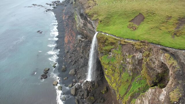 Waterfall falling into the sea in Iceland, view from above.