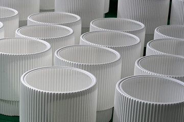 A group of modern, white, fluted cylindrical plant pots arranged on a green surface. Perfect for interior design, gardening, home decor, and retail display concepts. © DRBURHAN