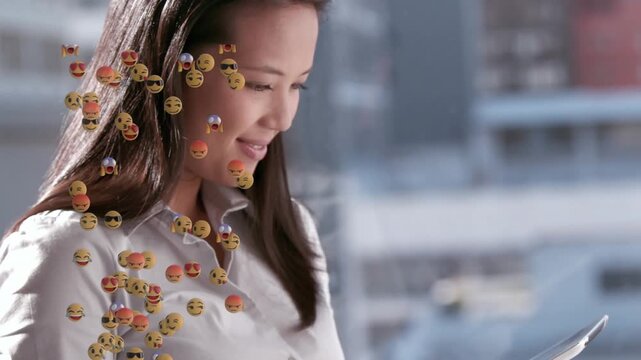 Animation of emoji icons over asian businesswoman using tablet