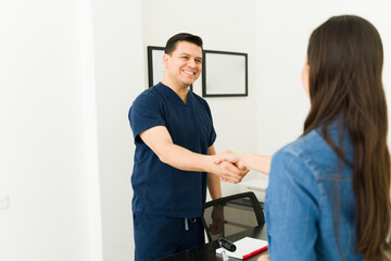 Obraz premium Doctor and patient shaking hands at medical clinic, starting a consultation about healthcare services