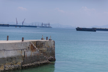 Fototapeta premium Tranquil Harbor Scene with Cargo Ships Under Clear Blue Sky
