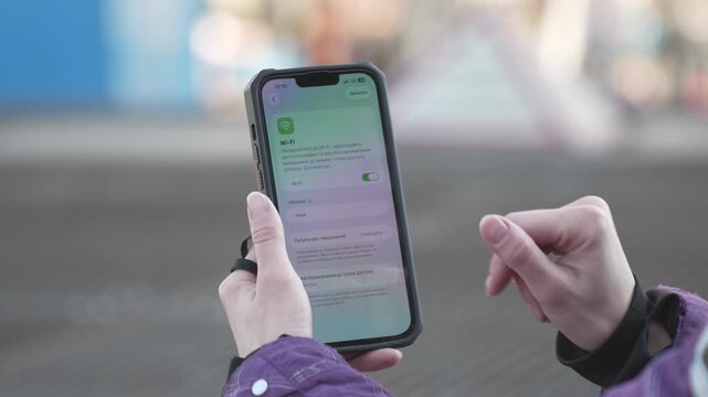 Close-up of Woman Hands Scrolling Wi-Fi Networks on Smartphone Outdoors