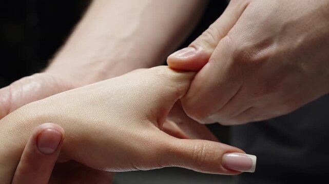 Close-up showing a gentle hand massage with focused thumb pressure on the palm and fingers, highlighting touch, tension relief, and therapeutic technique in a calming setting