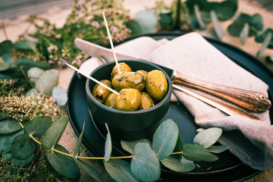 Green olives in an aromatic herb marinade. Mediterranean-table decoration for a appetizer. Close-up.