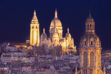 Fototapeta premium Illuminated hilltop basilica above Paris rooftops at night