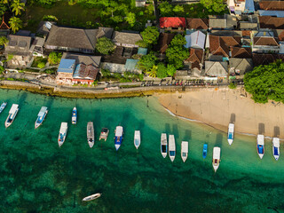 Top down view of traditional boats anchored in turquoise water near a tropical island town © whitcomberd