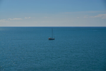 Fototapeta premium Solitary sailboat drifting on blue waters