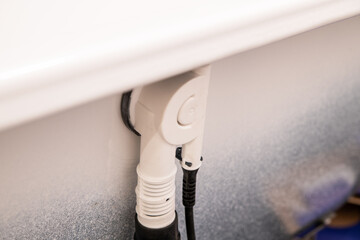 Closeup of white bathtub drain and plumbing connection under rim