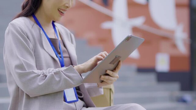 A cheerful businesswoman stands in her office, using a digital tablet to work on a financial project.