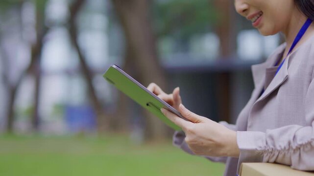 A cheerful businesswoman stands in her office, using a digital tablet to work on a financial project.