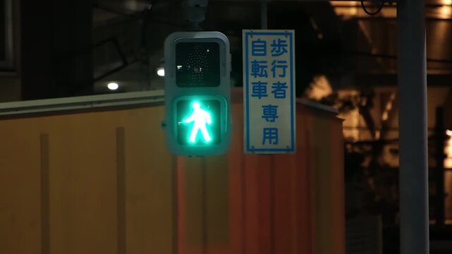 Pedestrian traffic signal in Tokyo, Japan, changing from green walking man to red standing man at night