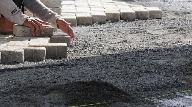 Workers strike pressed bricks together during installation to demonstrate durability, strength, and quality of machine pressed bricks used in modern construction projects.